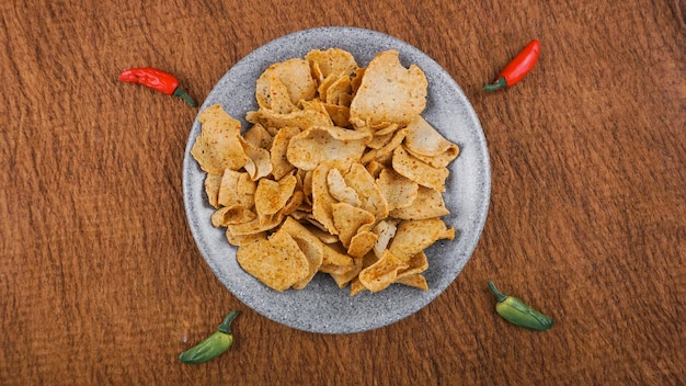 Flatlay-Ansicht von Basreng Indonesischer traditioneller Snack aus gebratenem Fleischbällchen mit Chilipulver zum Würzen, serviert auf grauer runder Steinplatte