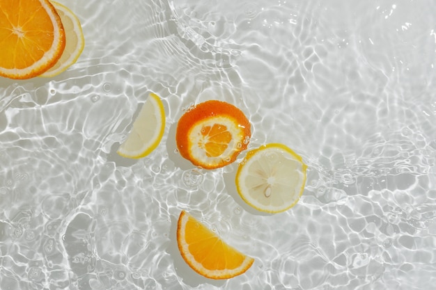 Flatlay aus transparentem, plätscherndem Wasser mit Orangen- und Zitronenscheiben