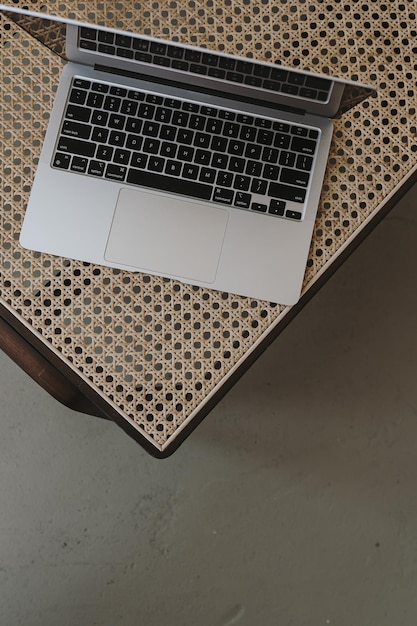 Flatlay de computadora portátil en un sillón de mimbre de lujo Trabajo en casa independiente compras en línea tienda en línea blog redes sociales concepto de marca