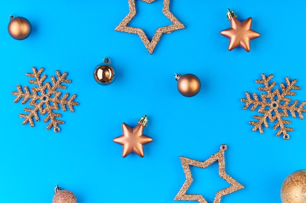 Flatlay de copos de nieve decorativos plateados y dorados, estrellas y bolas sobre fondo azul con copyspace para su texto o anuncio de Navidad