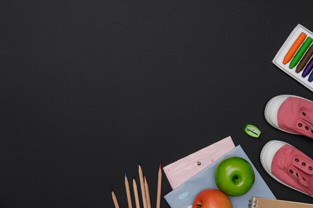 Flatlay criativo da mesa de educação verde com livros de estudante, sapatos, espaço vazio colorido lápis no fundo do quadro-negro, conceito de educação e volta às aulas