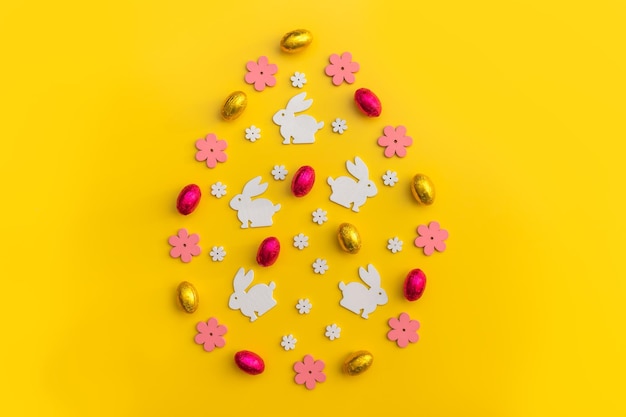 Flatlay decoración de Pascua flores de madera conejos y eggtulips sobre fondo amarillo espacio de copia