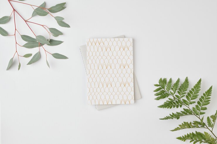 Foto flatlay do notebook no laptop dobrado contra o espaço em branco cercado por galhos com folhas verdes