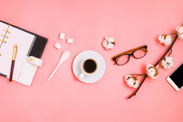 Flatlay de espresso, planificador y smartphone en rosa