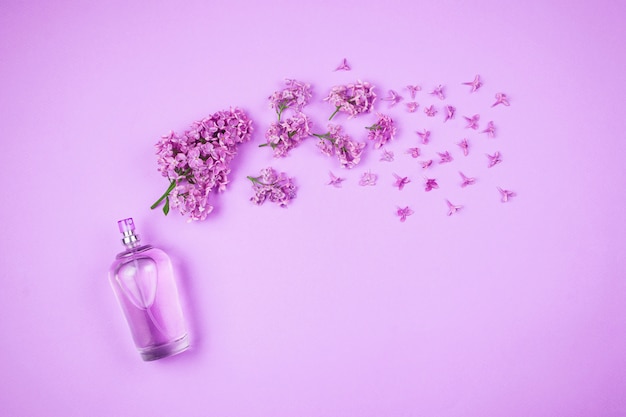 Flatlay con flores violetas lilas y frasco de perfume