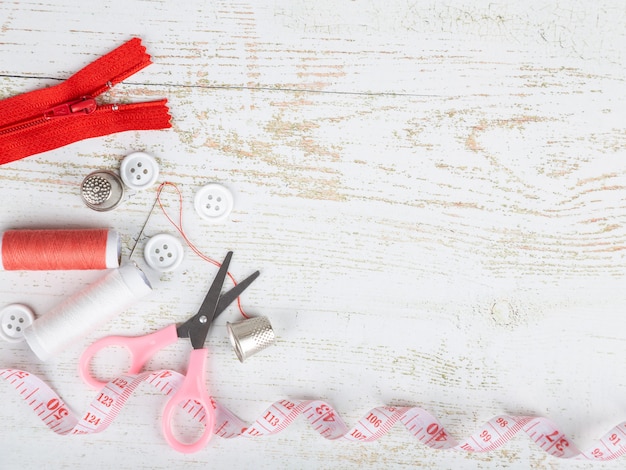 Flatlay de herramientas para la costura y costura sobre fondo de madera blanco