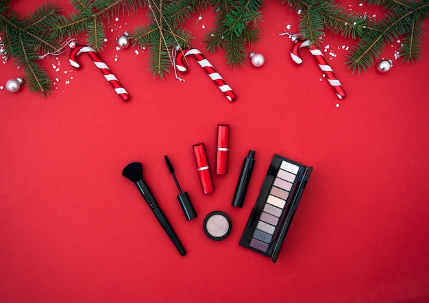 Flatlay-Komposition mit Make-up-Kosmetikprodukten Weihnachtsdekor auf rotem Hintergrund Beauty-Banner