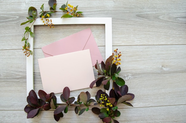 Foto flatlay con marco de madera blanco y maqueta y copyspace sobres rosados pastel y tarjeta en blanco