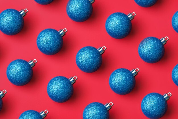 Flatlay mínimo de patrón de adorno de bola de Navidad azul sobre fondo rojo vista superior