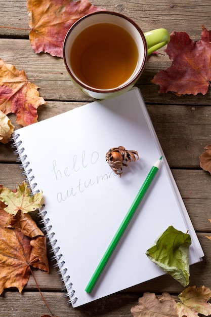 Flatlay de otoño sobre fondo de madera con una taza de té