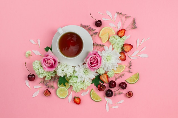 Flatlay de taza de té caliente con varias bayas y flores