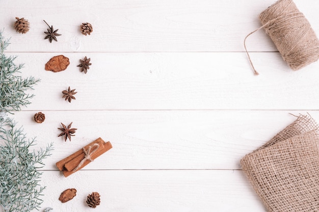 Flatlay. Zimt, Tannenzweige auf weißem hölzernem Hintergrund, Gewebe und Threads für das Geschenkverpacken