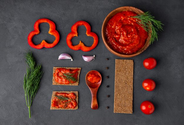 Flatlet com pimenta aperitivo ajvar e ingredientes em um espaço escuro