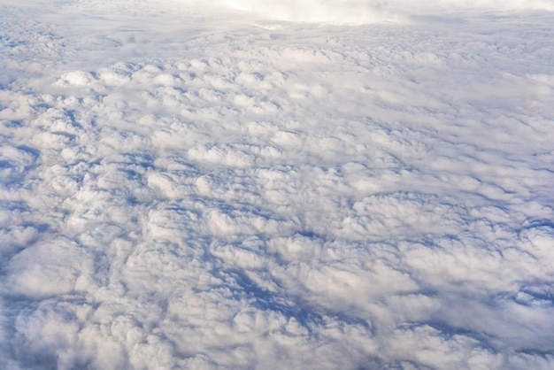 Flaumige Wolken, die so flach aussehen, wie sie von einem Verkehrsflugzeug aus gesehen werden