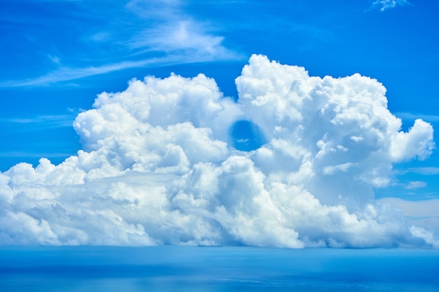 Flauschige weiße Wolken über blauem Meerwasser.