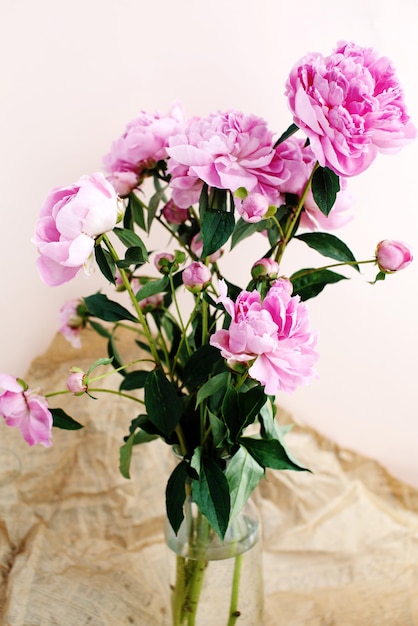 Flauschiger Blumenstrauß aus rosa Pfingstrosen blüht im Sonnenlicht auf zerknittertem Bastelpapier Hintergrund Valentinstag und Frauentag Hintergrund