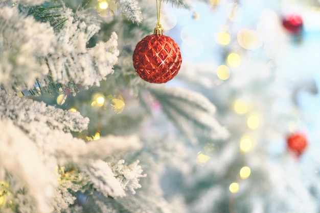 Foto flauschiger, künstlicher, schneebedeckter, frostiger weihnachtsbaum, verziert mit roten, leuchtenden kugeln und feenhaften lichtern. vintage weihnachtsschmuck