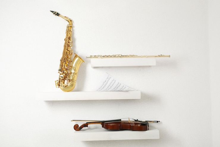Foto flauta de violín y saxofón en estantes decorados con fondo de pared blanca