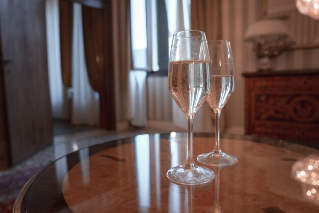 Flautas de champanhe elegantes em mesa marrom em um quarto de hotel de luxo com fundo de lustre