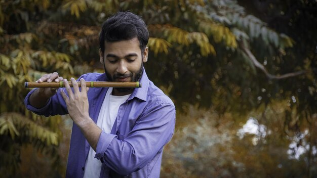 Flautista tocando la flauta durante el otoño - Imágenes de flautista guapo indio