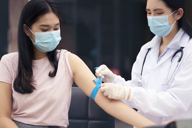 Flebotomista experimentado preparando torniquete a una mujer para extracción de sangre