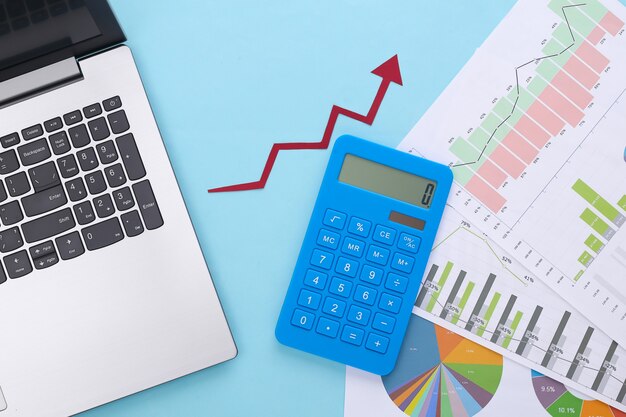 Flecha hacia arriba de crecimiento, gráficos y tablas con computadora portátil y calculadora en azul