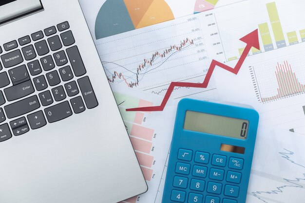 Flecha ascendente de crecimiento, gráficos y tablas con computadora portátil y calculadora