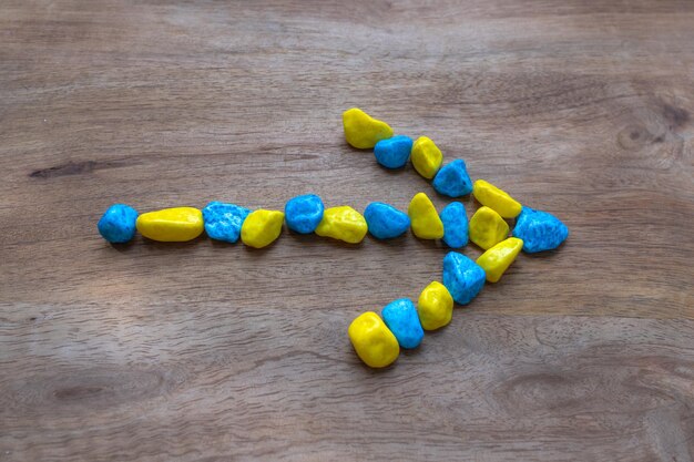 Una flecha hecha de piedras pequeñas Fondo de madera Colores de la bandera ucraniana Símbolo de movimiento