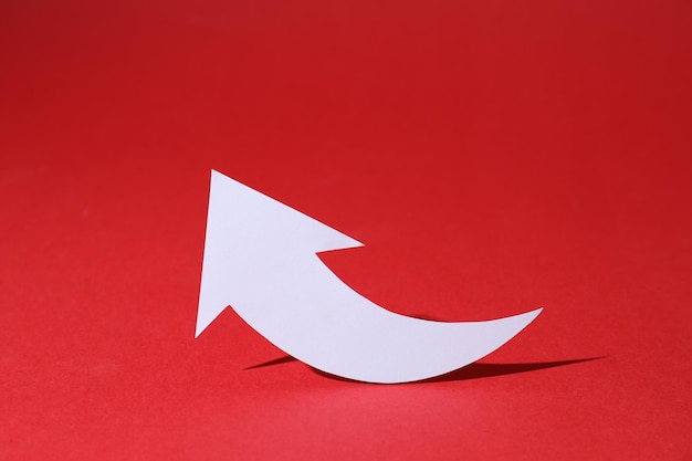Flecha de papel curvo blanco sobre fondo rojo