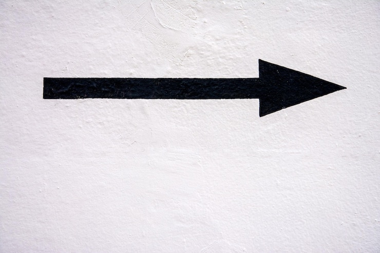Foto flecha pintada de negro sobre un fondo blanco brillante
