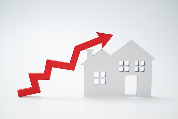 Una flecha roja hacia arriba y una casa El concepto del aumento del precio de los bienes raíces