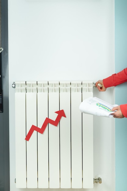 Flecha roja de aumento de precio en radiador de calefacción Mujer con factura cierra calefacción Foto vertical