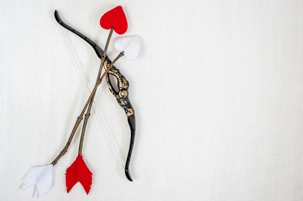 Foto las flechas y el arco de cupid en un fondo de madera blanco.