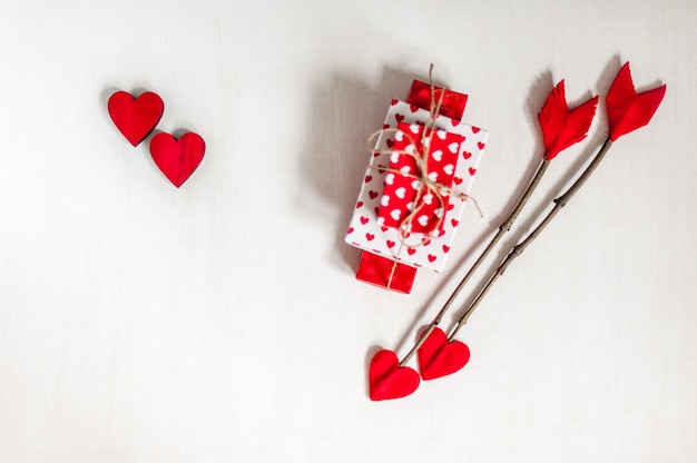 Foto flechas de la ramita del día de tarjetas del día de san valentín en el fondo de madera blanco con las cajas de regalo y los corazones rojos.