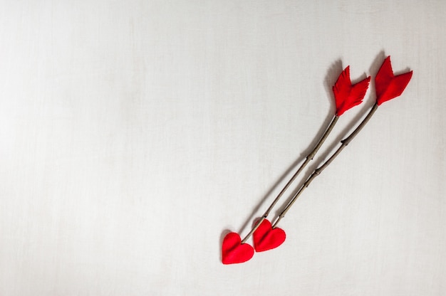 Flechas de la ramita del día de tarjetas del día de San Valentín en el fondo de madera blanco. Flechas de Cupido hechas a mano.