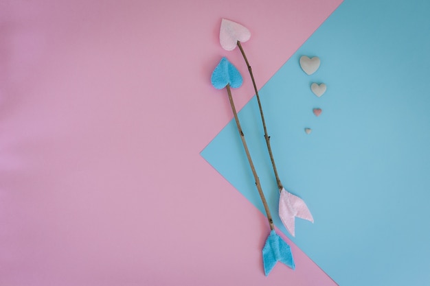 Flechas de la ramita del día de tarjetas del día de San Valentín en fondo rosado y azul con el corazón