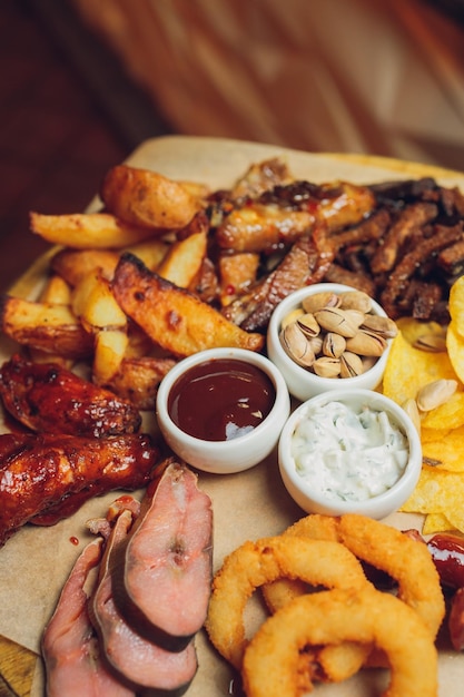 Fleisch auf einem Holzbrett gebratene Hähnchenflügel Schweinerippchen gegrilltes Gemüse Pommes frites Bier Vorspeise mit Soßen Hintergrundbild