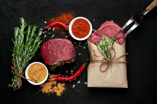 Fleisch aus einer Metzgerei, zwei Steaks mit Zutaten. zwei Stücke Rindfleisch auf Beton schwarz