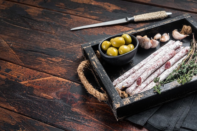 Fleisch Charcuterie Fuet Salamiwürste mit Oliven und Kräutern Holzhintergrund Draufsicht Kopierbereich