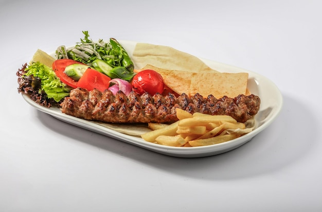 FLEISCH-Kebab-Platte mit Salatpommes und Pita-Brot, serviert in der Seitenansicht des arabischen Essens