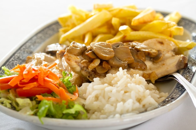 Fleisch mit Champignons, Salat, Reis und Kartoffeln