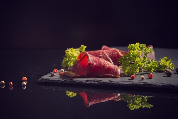 Fleisch mit Gemüse auf einem schwarzen Tisch geschnitten