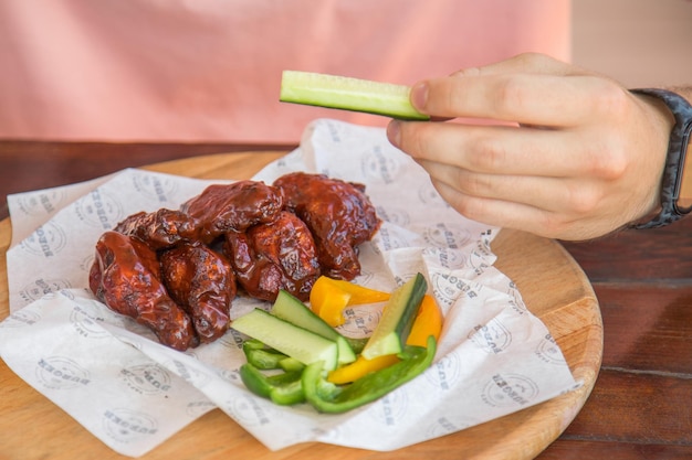 Fleisch und Salat und Mann mit Mann, der Fleisch mit Salat isst, der Hähnchen am Tisch im Freien schnitzt