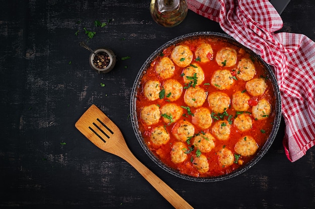 Fleischbällchen in Tomatensauce in einer Pfanne auf dunklem Hintergrund. Ansicht von oben, flach.