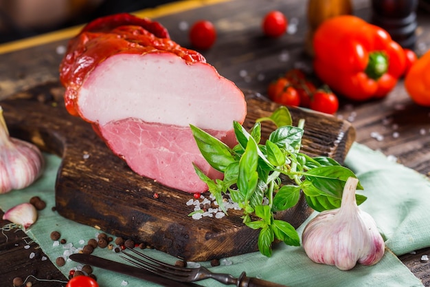 Fleischdelikatesse, gekochtes Schweinefleisch schön, ganz oder in Scheiben geschnitten auf einem Küchenschneidebrett, Gewürze