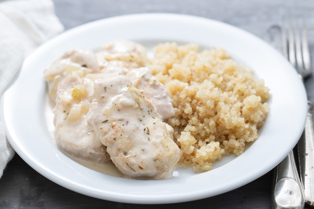 Fleischgericht mit Sauce und gekochter Quinoa auf weißem Holz