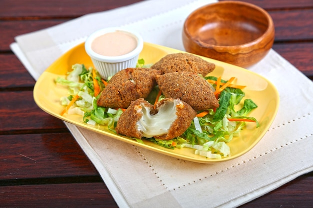 Fleischkäse-Kubbe oder Fleischkäse-Kibbe mit Salat und Dip, serviert in Gerichten, isoliert auf Tischseitenansicht von Speisen aus dem Nahen Osten