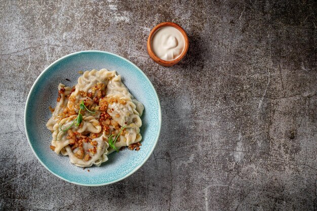 Fleischknödel mit Gewürzen auf einem Teller mit Grüns vor dem Hintergrund eines grauen Steintisches