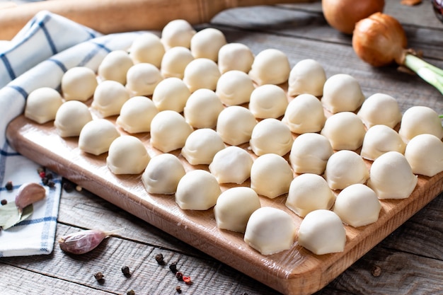 Fleischknödel - russische Pelmeni auf hölzernem Hintergrund