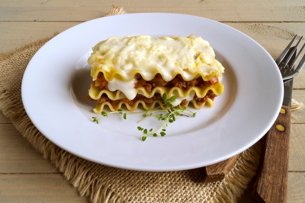 Fleischlasagne auf einem hölzernen Hintergrund.